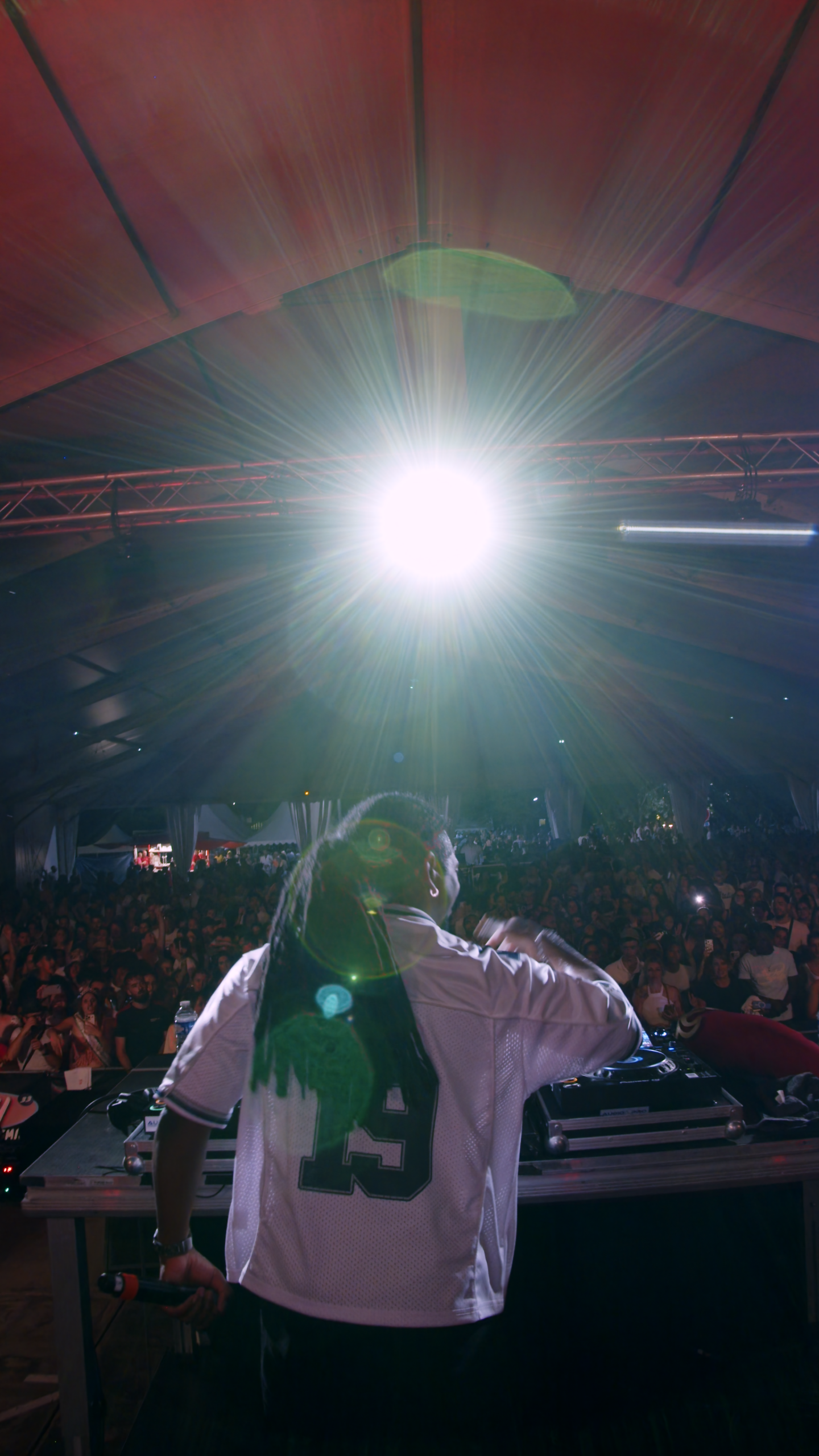 Un DJ se produit devant une foule enthousiaste lors d'un événement musical à Bordeaux, sous un éclairage dynamique.
