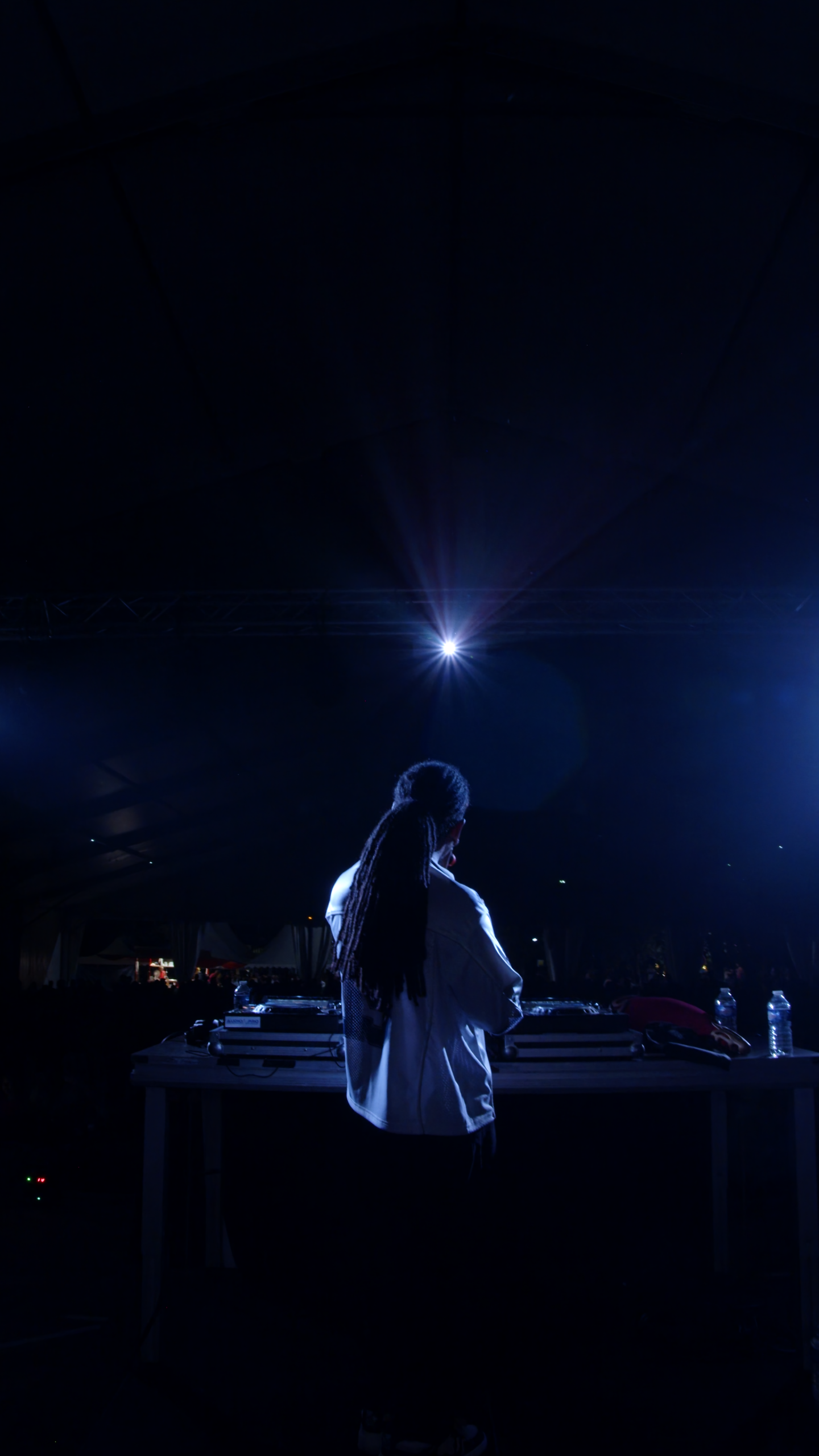 Un DJ en performance sur scène, éclairé par des lumières vives, dans une ambiance de festival à Bordeaux.