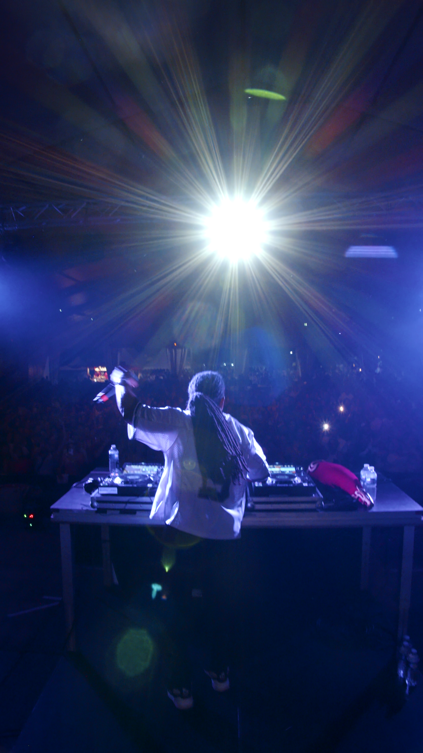 Un DJ sur scène avec des lumières vives, animant une foule enthousiaste lors d'un événement musical à Bordeaux.